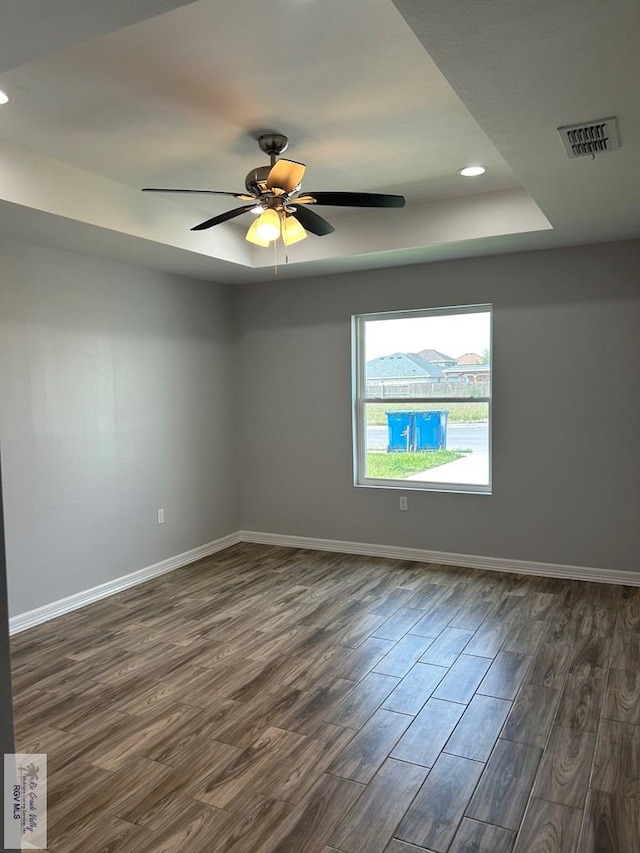 spare room with visible vents, baseboards, a raised ceiling, and dark wood-type flooring