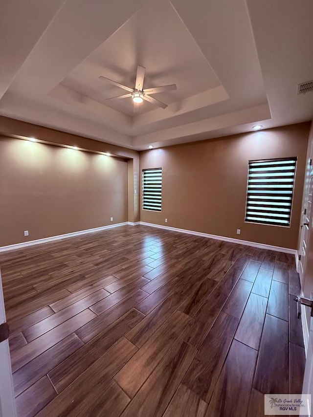 empty room featuring a tray ceiling, wood-type flooring, and ceiling fan