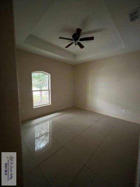 tiled spare room with a raised ceiling and ceiling fan