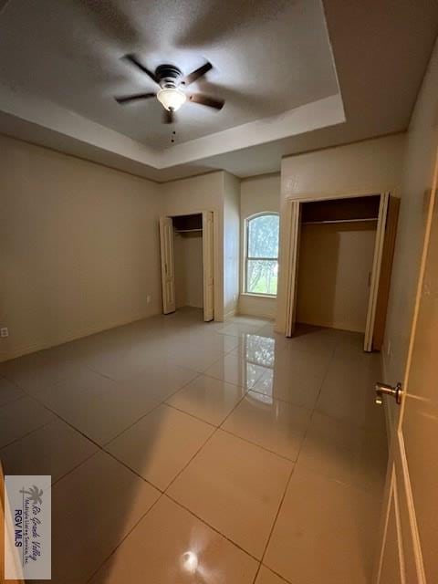 tiled spare room with a raised ceiling and ceiling fan