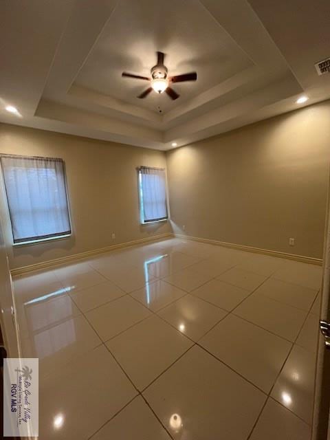 tiled spare room with a raised ceiling and ceiling fan