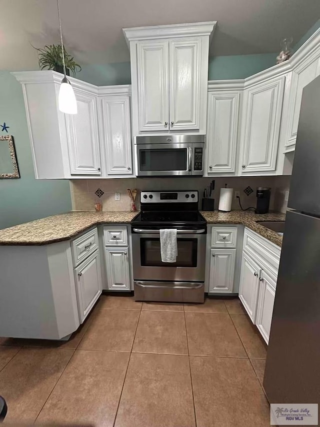 kitchen featuring hanging light fixtures, tile patterned floors, white cabinets, and appliances with stainless steel finishes