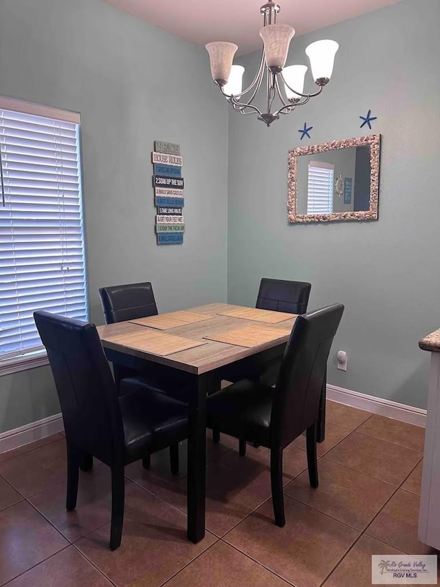 dining space with dark tile patterned floors and a notable chandelier