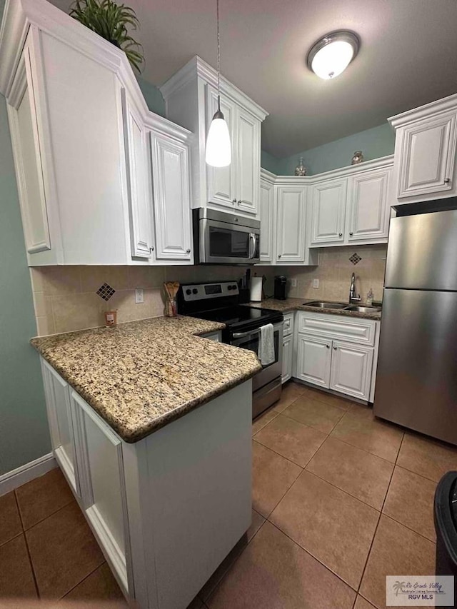 kitchen featuring appliances with stainless steel finishes, decorative light fixtures, sink, and white cabinets