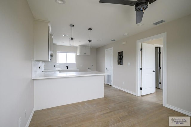 kitchen featuring kitchen peninsula, ceiling fan, decorative light fixtures, light hardwood / wood-style floors, and white cabinetry