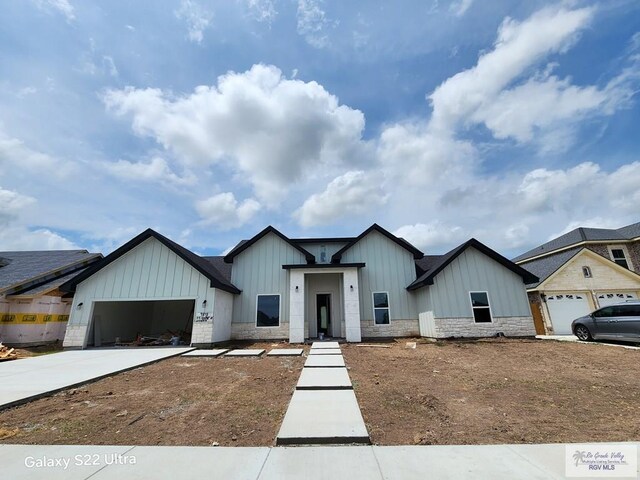 9848 Heights N, Harlingen, TX 78552 - view of front of house featuring board and batten siding, a garage, stone siding, and driveway