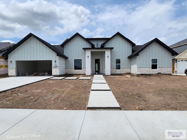 9848 Heights N, Harlingen, TX 78552 - view of front of house with board and batten siding, a garage, stone siding, and driveway