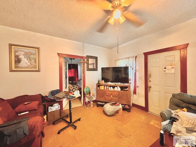 living room featuring ceiling fan and a textured ceiling