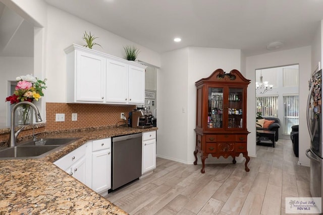 kitchen featuring stainless steel appliances, backsplash, light wood-style flooring, white cabinetry, and a sink