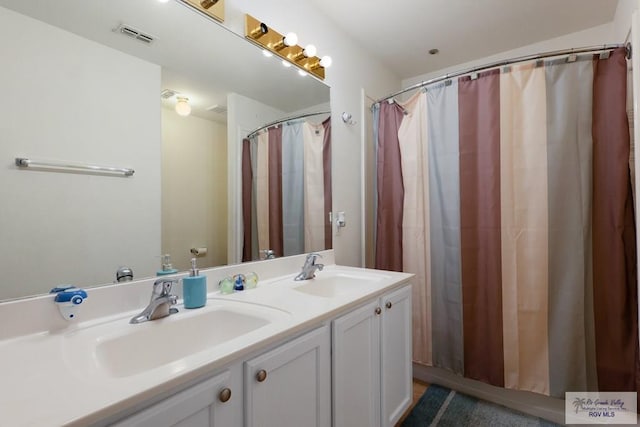 bathroom with double vanity, visible vents, and a sink