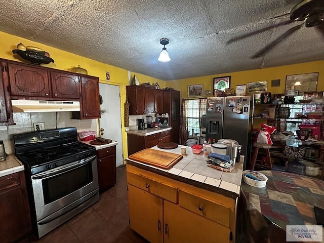 kitchen featuring tile counters, stainless steel appliances, dark tile patterned floors, a textured ceiling, and dark brown cabinets