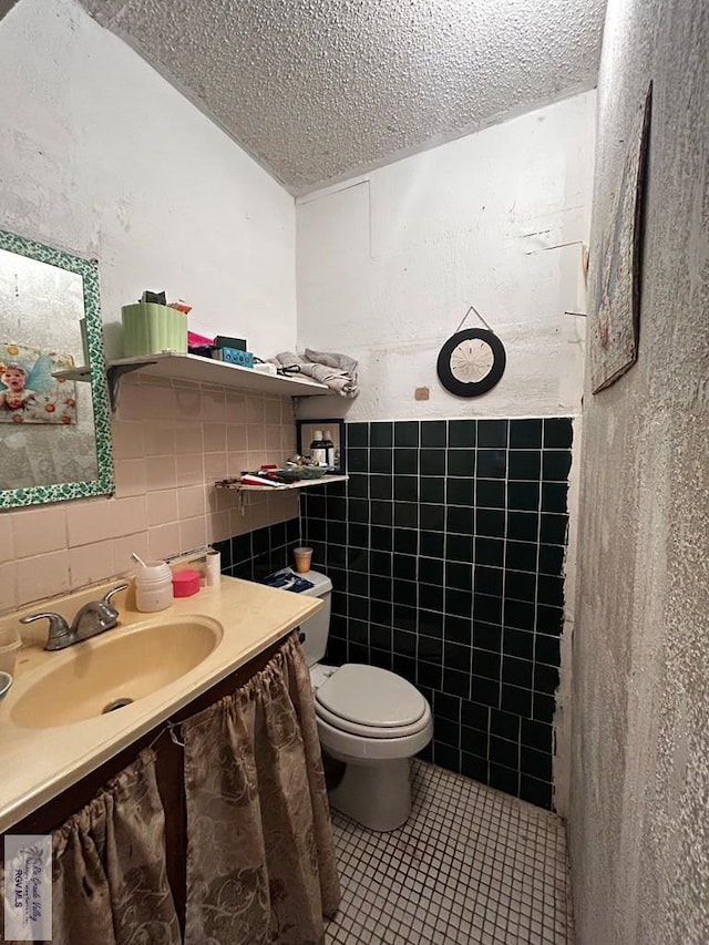 bathroom featuring a textured ceiling, vanity, tile walls, and toilet