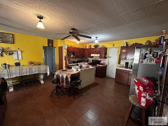 kitchen with ceiling fan, dark tile patterned floors, stainless steel appliances, and a textured ceiling