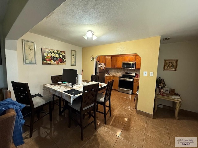 tiled dining area with a textured ceiling