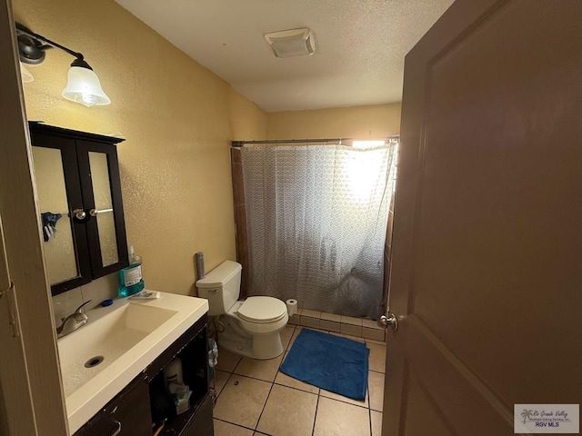 full bath featuring vanity, curtained shower, a textured wall, tile patterned flooring, and toilet