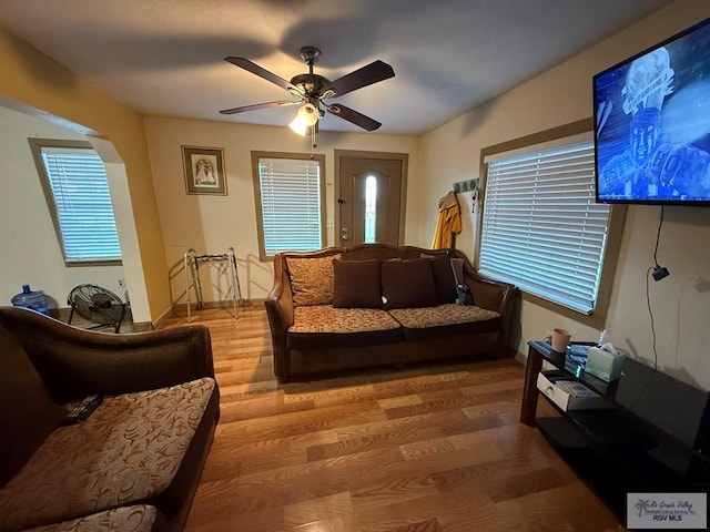 living room with baseboards, a ceiling fan, arched walkways, and wood finished floors