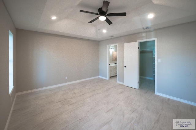 23919 Ellie Ln, Harlingen, TX 78552 - unfurnished bedroom featuring a spacious closet, a closet, a ceiling fan, ensuite bath, and baseboards