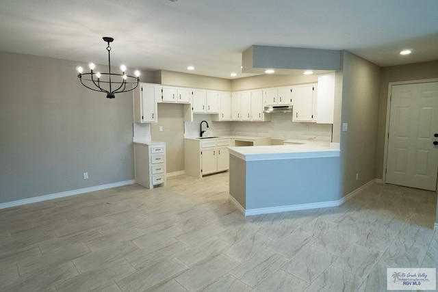 23919 Ellie Ln, Harlingen, TX 78552 - kitchen featuring under cabinet range hood, a chandelier, recessed lighting, white cabinets, and baseboards