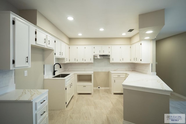 23919 Ellie Ln, Harlingen, TX 78552 - kitchen with a sink, under cabinet range hood, decorative backsplash, a peninsula, and white cabinets