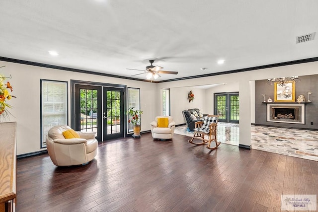 sitting room with a wealth of natural light, french doors, dark wood-type flooring, and ceiling fan with notable chandelier