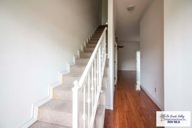 staircase with hardwood / wood-style flooring and ceiling fan