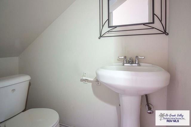 bathroom featuring lofted ceiling, sink, and toilet