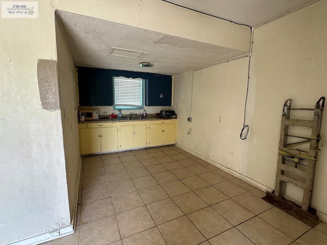 404 Riverside Blvd, Brownsville, TX 78520 - kitchen with a sink, white microwave, light tile patterned flooring, and a textured ceiling