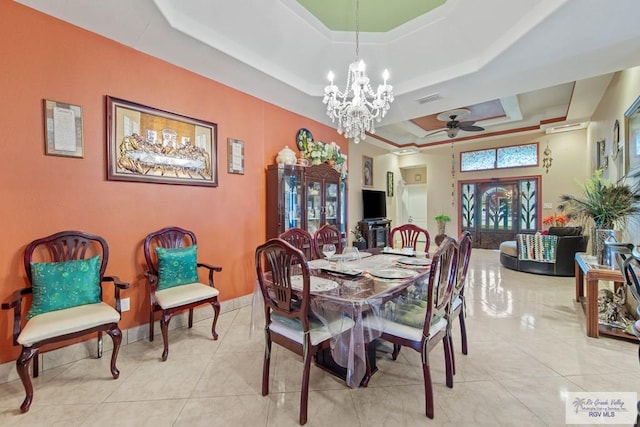 tiled dining space featuring a tray ceiling and ceiling fan with notable chandelier