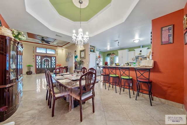 tiled dining space featuring a raised ceiling and a chandelier