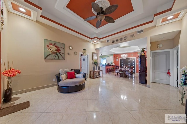 sitting room with a tray ceiling, ceiling fan with notable chandelier, and light tile patterned floors