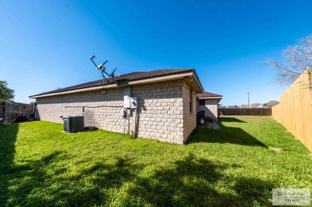 view of property exterior with central AC, a yard, and a fenced backyard