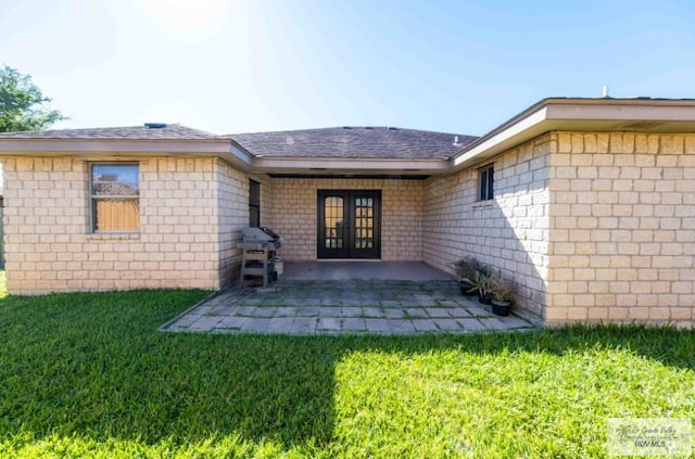 back of house featuring french doors, roof with shingles, a patio, and a lawn