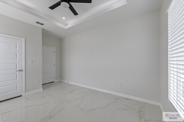 unfurnished bedroom with baseboards, visible vents, a tray ceiling, and marble finish floor