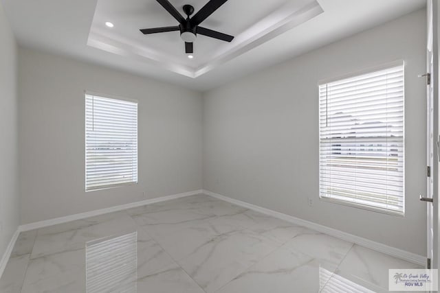 empty room with recessed lighting, marble finish floor, ceiling fan, baseboards, and a raised ceiling