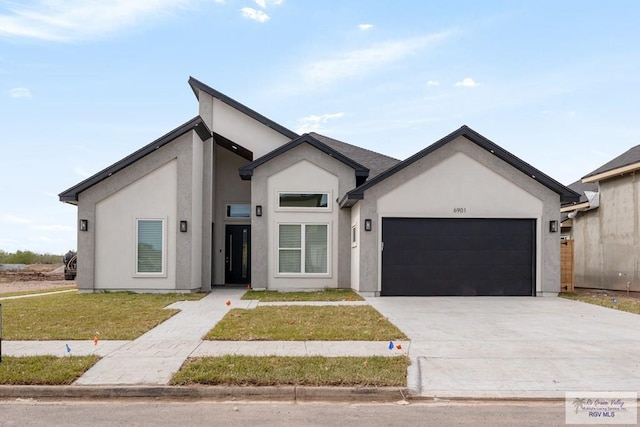 view of front of property with stucco siding, concrete driveway, a front yard, and an attached garage