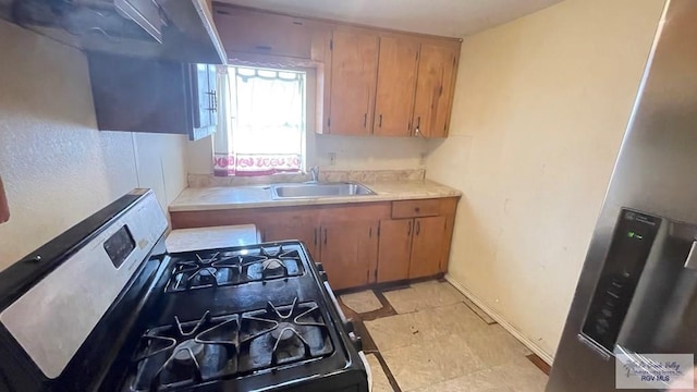 kitchen featuring stainless steel fridge, gas stove, and sink