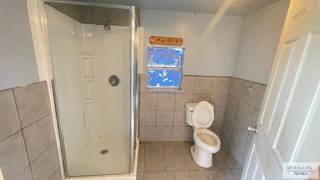 bathroom featuring tile patterned floors, a shower with shower door, tile walls, and toilet