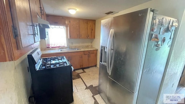 kitchen with black range with gas stovetop, stainless steel refrigerator with ice dispenser, and sink