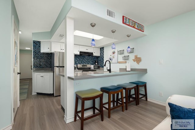 200 Padre Blvd Unit 1206, South Padre Island, TX 78597 - kitchen featuring stainless steel appliances, under cabinet range hood, a peninsula, and wood finished floors