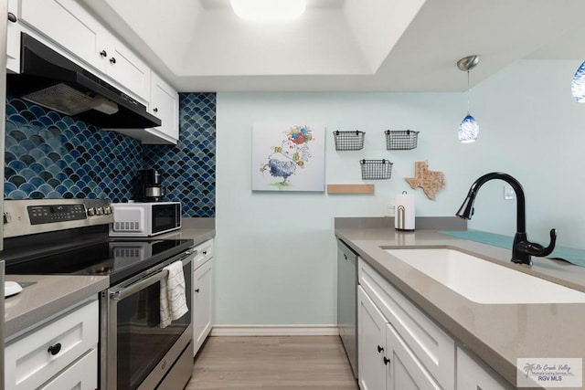 200 Padre Blvd Unit 1206, South Padre Island, TX 78597 - kitchen featuring stainless steel appliances, under cabinet range hood, a sink, light wood finished floors, and white cabinetry