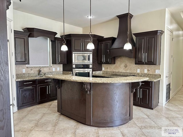 kitchen with custom exhaust hood, hanging light fixtures, dark brown cabinets, and appliances with stainless steel finishes