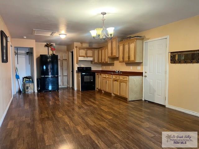 1327 W Johnson Ave, Harlingen, TX 78550 - kitchen with black appliances, dark wood-type flooring, under cabinet range hood, baseboards, and dark countertops