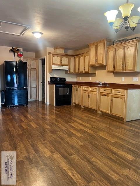 1327 W Johnson Ave, Harlingen, TX 78550 - kitchen with black appliances, under cabinet range hood, dark wood-type flooring, dark countertops, and a chandelier