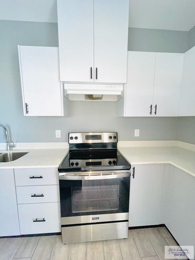 kitchen featuring electric range, light hardwood / wood-style floors, white cabinets, and sink