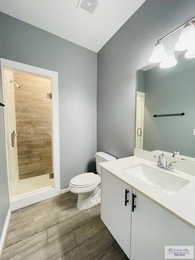 bathroom featuring a shower, vanity, wood-type flooring, and toilet