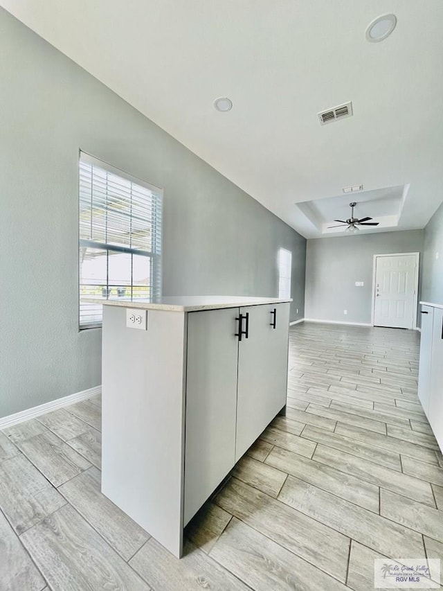 kitchen featuring white cabinets, ceiling fan, a kitchen island, and light hardwood / wood-style flooring