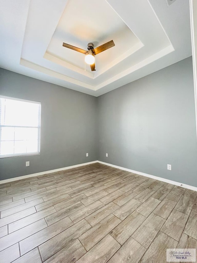 spare room featuring light hardwood / wood-style floors, a raised ceiling, and ceiling fan