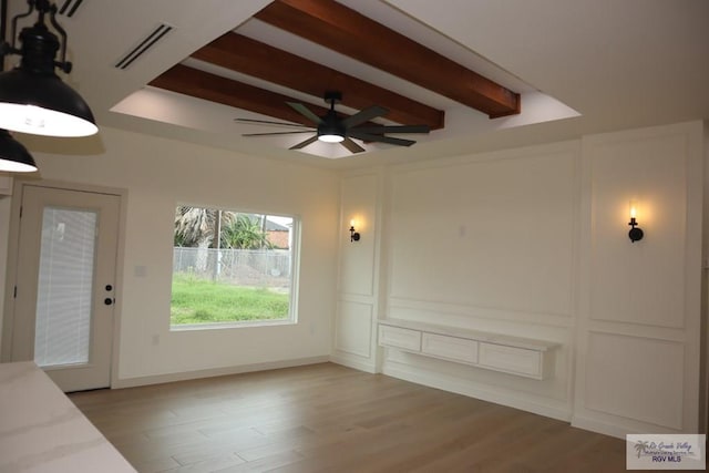 13953 Isaiah Ct, La Feria, TX 78559 - unfurnished living room featuring a ceiling fan, beam ceiling, a decorative wall, and light wood-style floors