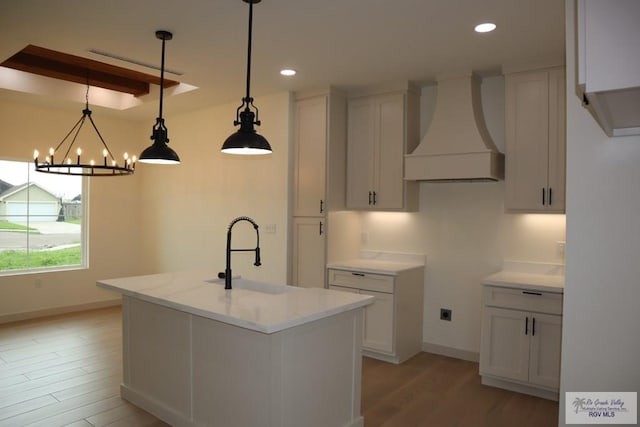 13953 Isaiah Ct, La Feria, TX 78559 - kitchen featuring custom exhaust hood, light wood-style flooring, recessed lighting, a chandelier, and a center island with sink