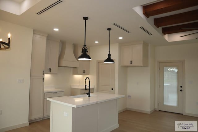 13953 Isaiah Ct, La Feria, TX 78559 - kitchen with premium range hood, light wood finished floors, white cabinetry, and recessed lighting